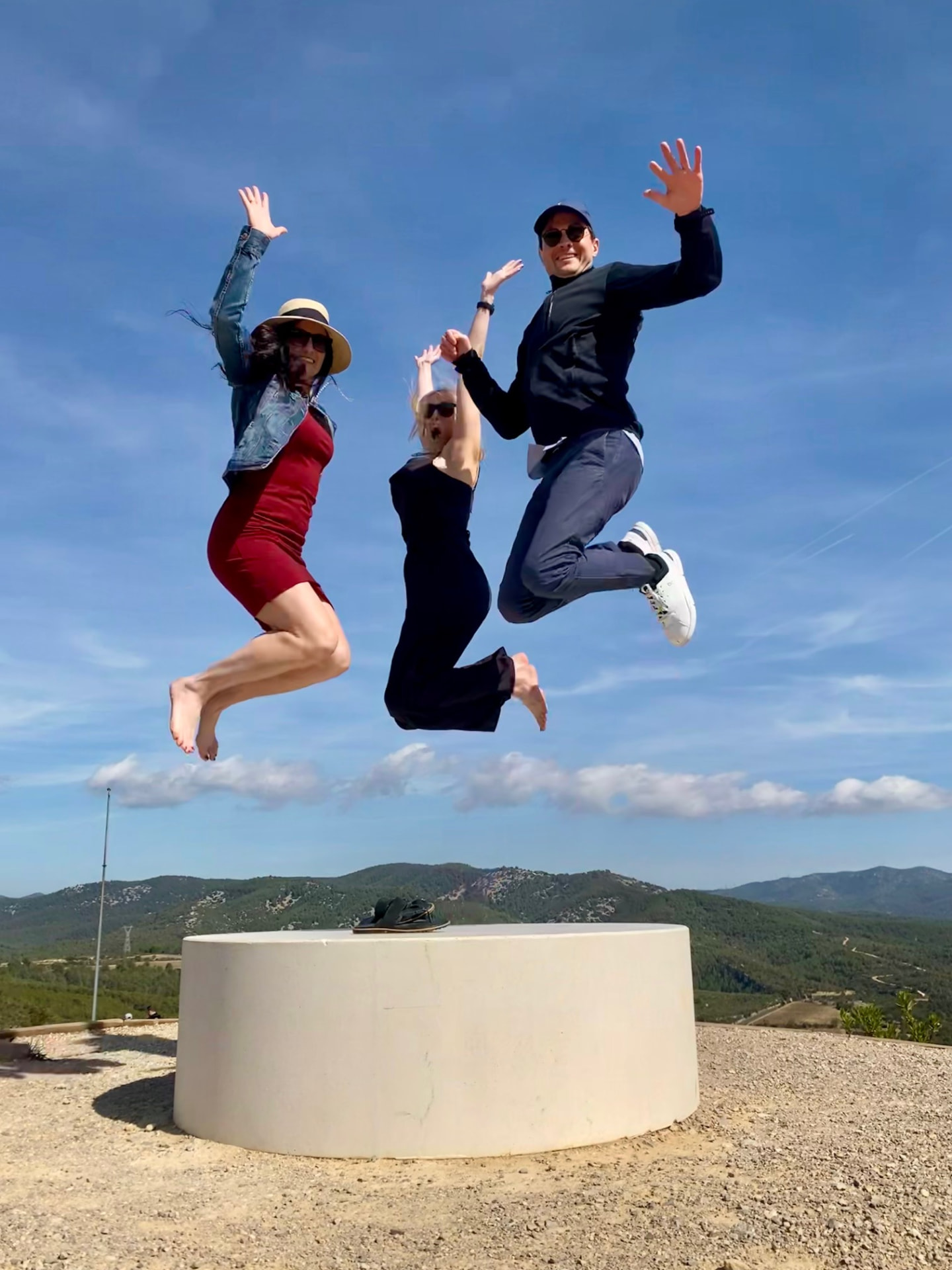 Three guests jumping for joy at a hilltop viewpoint above the Penedès vineyards during a private wine tour with a WSET Level 3 certified Cava expert and private wine guide