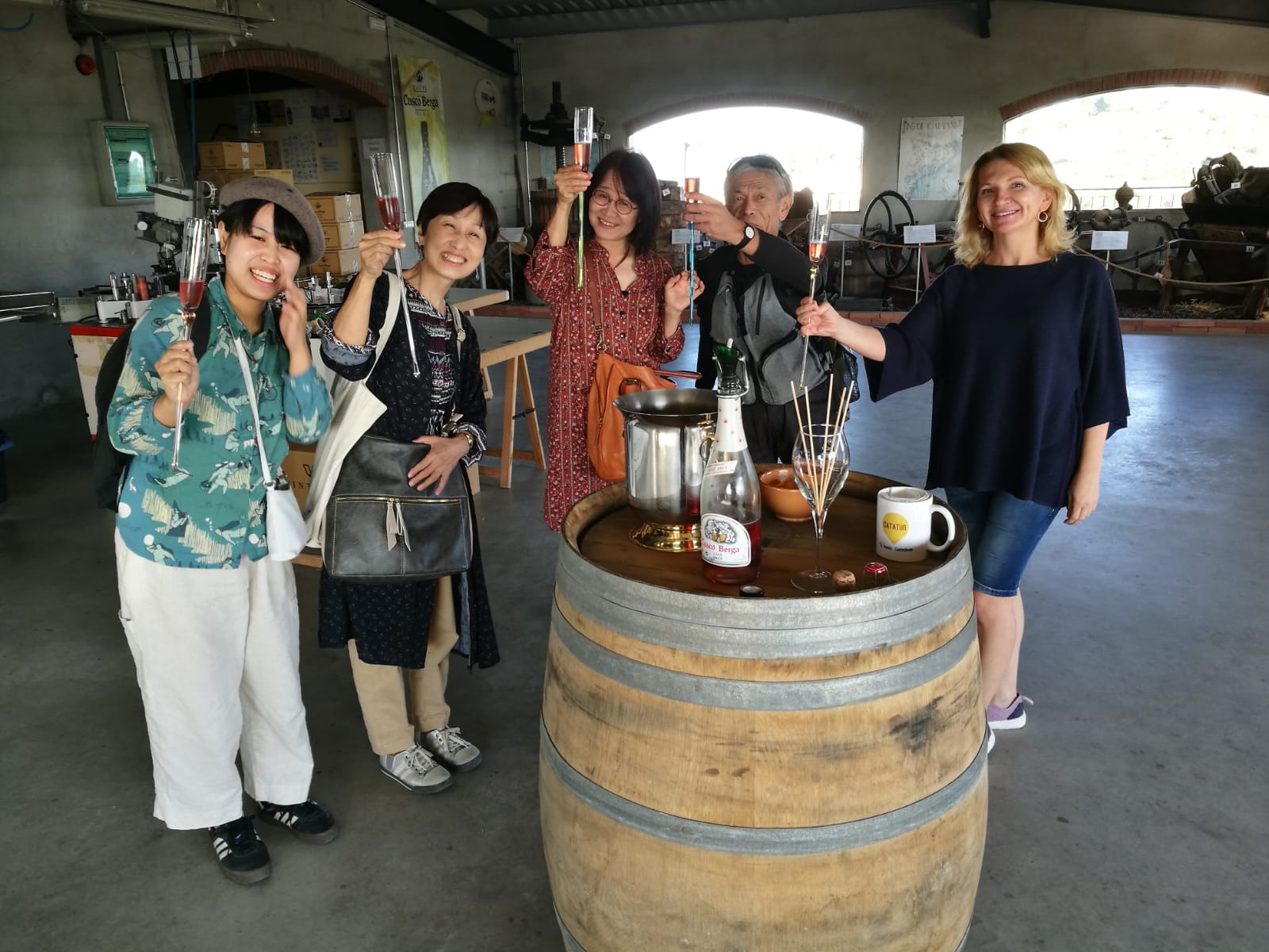 Group toasting with Cava rosé around a wine barrel in a rustic Penedès cellar on a private tour with a WSET Level 3 certified Cava expert and private wine guide