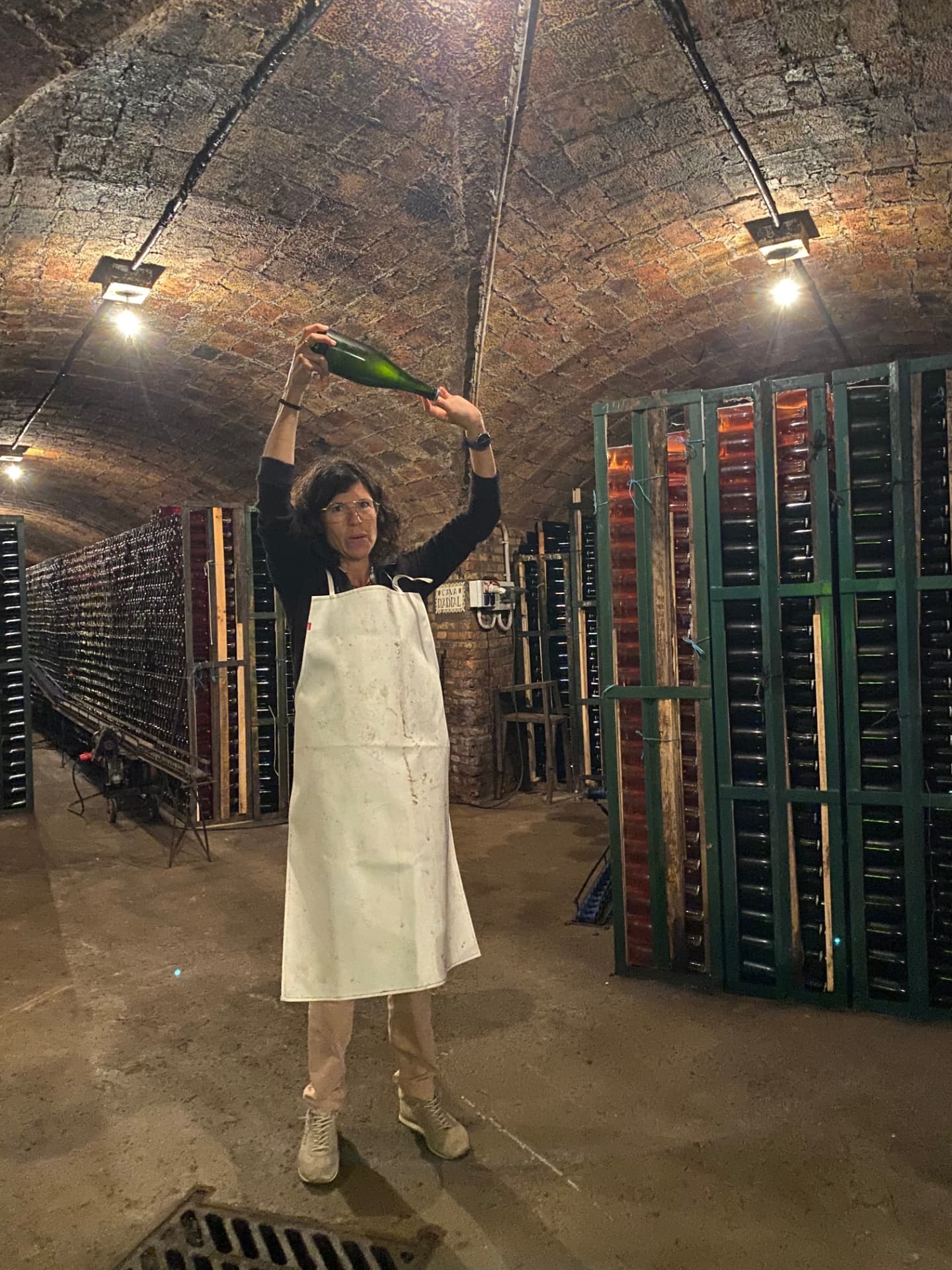 Guide demonstrating the riddling process with bottles in a vaulted underground Cava cellar visited on a private tour with a WSET Level 3 certified Cava expert and private wine guide