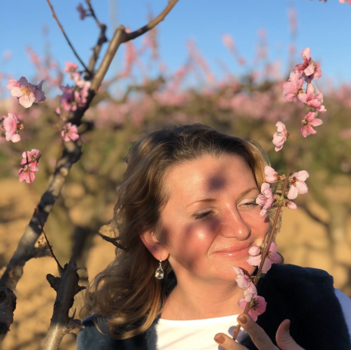 Spring peach blossoms framing a smiling guest at golden hour