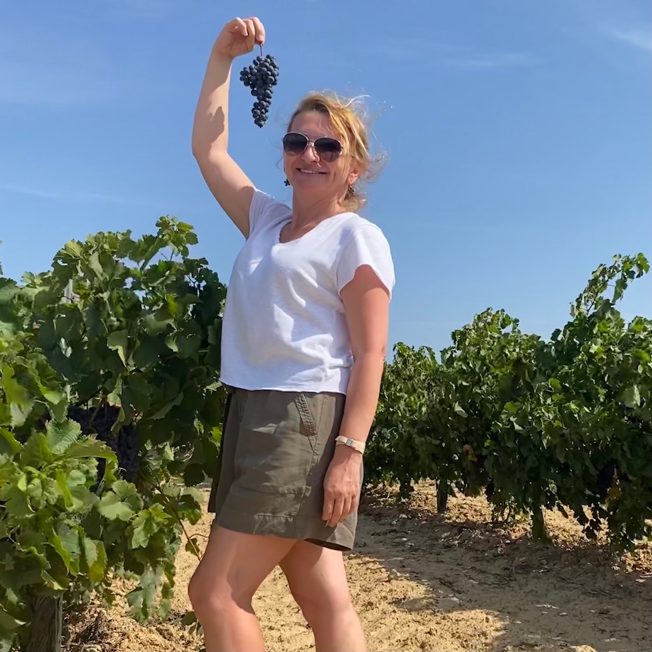 Guest holding up a freshly picked bunch of red grapes