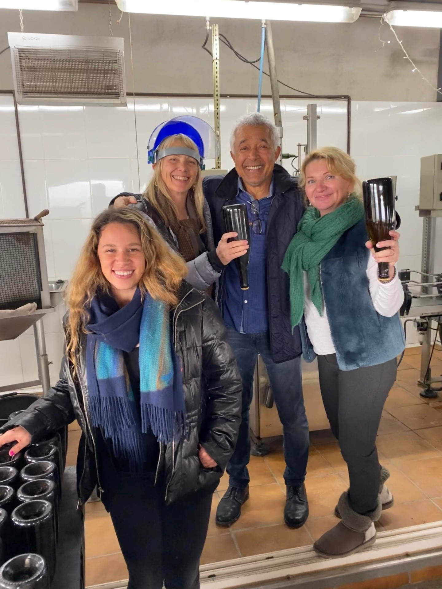 Group celebrating at the cava bottling line with fresh bottles in hand